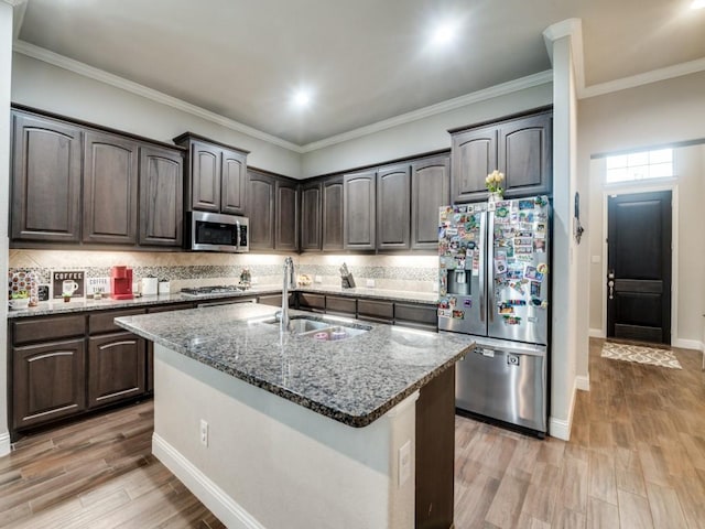 kitchen with a sink, light wood-type flooring, stone counters, and stainless steel appliances