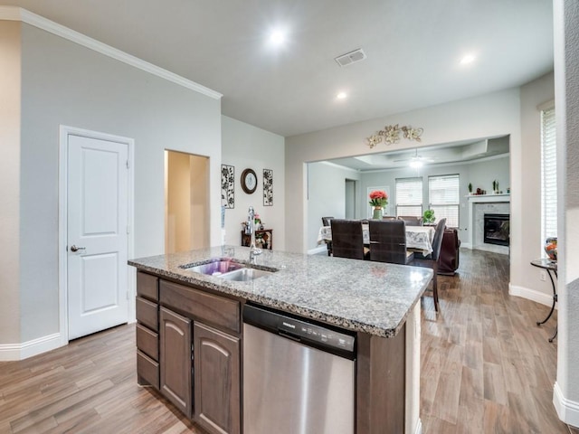 kitchen featuring a center island with sink, light wood-style floors, stainless steel dishwasher, and open floor plan