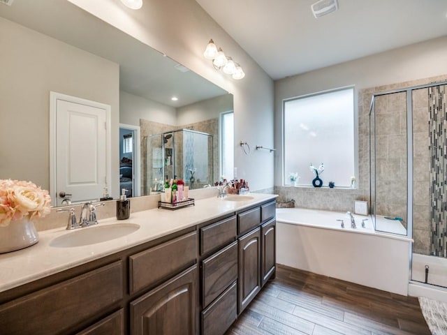 ensuite bathroom with visible vents, a shower stall, a garden tub, double vanity, and a sink