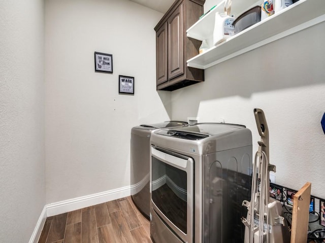 washroom featuring dark wood finished floors, cabinet space, baseboards, and washer and clothes dryer