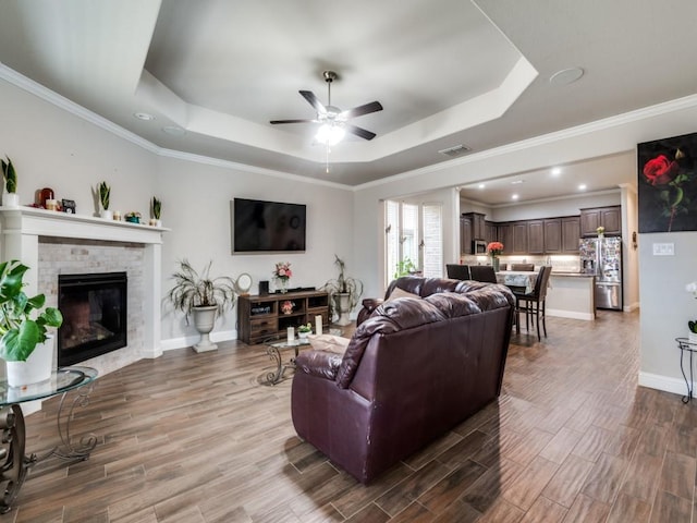 living room with a tray ceiling, wood finished floors, and ceiling fan