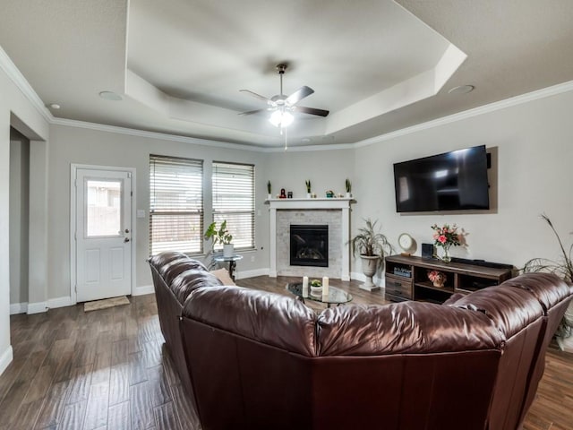 living room with ceiling fan, baseboards, a tray ceiling, and dark wood-style flooring