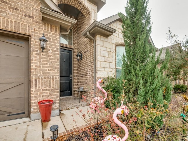 view of exterior entry featuring brick siding and stone siding