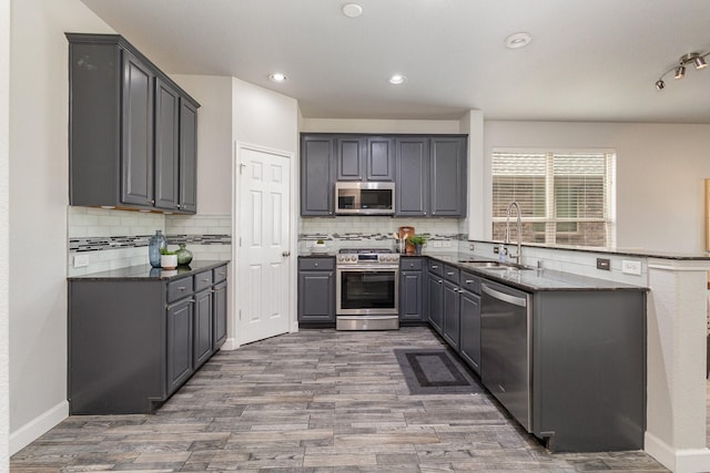 kitchen featuring gray cabinets, sink, dark stone countertops, stainless steel appliances, and dark wood-type flooring