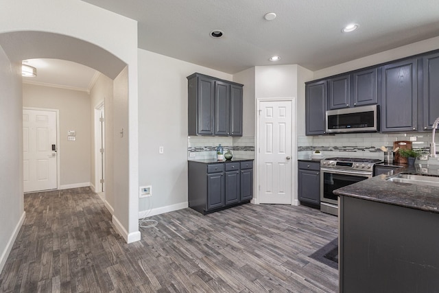 kitchen with dark wood-type flooring, stainless steel appliances, gray cabinets, and tasteful backsplash