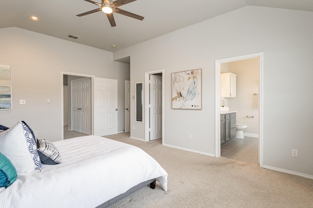 bedroom with light carpet, vaulted ceiling, ceiling fan, and ensuite bathroom