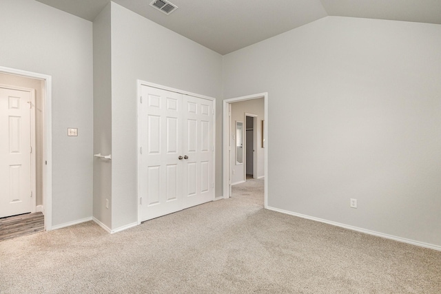 unfurnished bedroom with a closet, vaulted ceiling, and light carpet