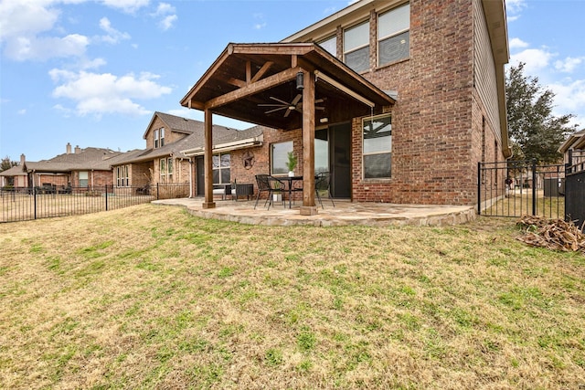 rear view of house with ceiling fan, a yard, and a patio