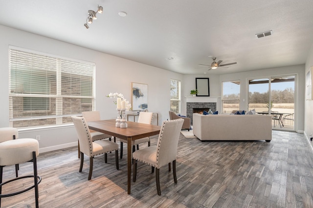 dining space featuring dark hardwood / wood-style flooring, ceiling fan, and a fireplace