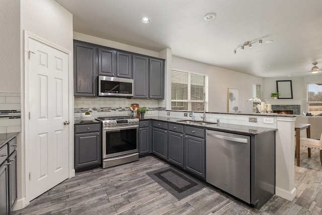 kitchen featuring sink, gray cabinetry, appliances with stainless steel finishes, kitchen peninsula, and backsplash