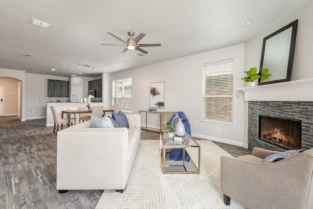 living room with dark hardwood / wood-style flooring, ceiling fan, and a fireplace