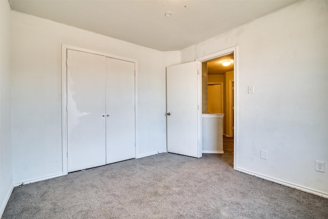 unfurnished bedroom featuring light colored carpet and a closet