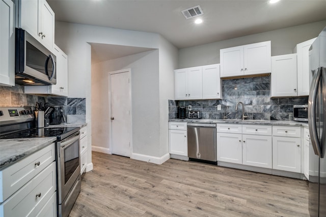 kitchen featuring white cabinetry, tasteful backsplash, appliances with stainless steel finishes, and light stone counters