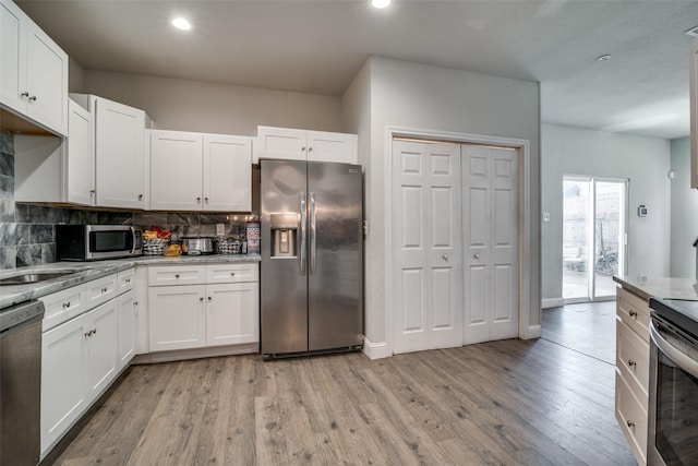 kitchen with appliances with stainless steel finishes, light stone countertops, decorative backsplash, and white cabinets