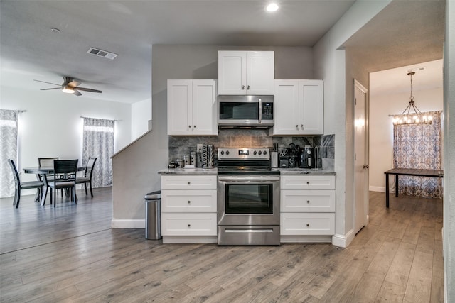 kitchen featuring backsplash, stainless steel appliances, hardwood / wood-style floors, and white cabinets