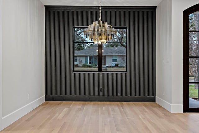 unfurnished dining area with an inviting chandelier and light wood-type flooring