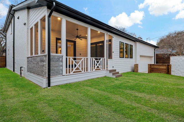 rear view of house with a lawn, fence, an attached garage, and a sunroom