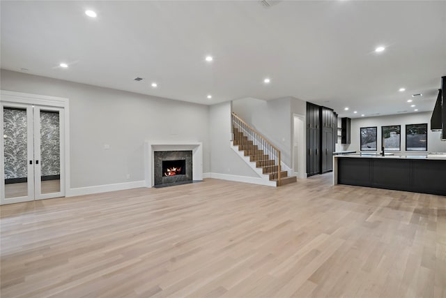 unfurnished living room with light hardwood / wood-style flooring, a high end fireplace, and french doors