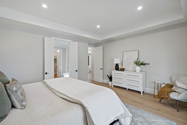 bedroom with light wood-style floors, recessed lighting, baseboards, and a tray ceiling