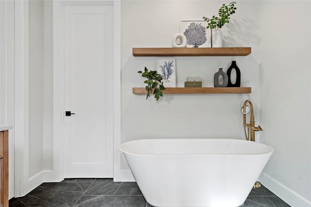 full bath featuring baseboards, marble finish floor, and a freestanding bath
