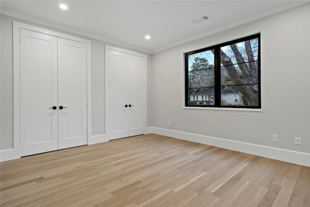 unfurnished bedroom with two closets and light hardwood / wood-style floors