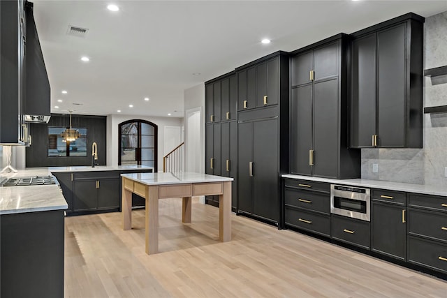 kitchen featuring tasteful backsplash, hanging light fixtures, light hardwood / wood-style flooring, and kitchen peninsula