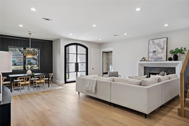 living area featuring visible vents, a fireplace, light wood-type flooring, an inviting chandelier, and recessed lighting