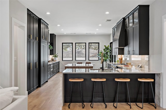 6716 Dalhart Ln, Dallas, TX 75214 - kitchen with dark cabinetry, light countertops, recessed lighting, a peninsula, and a breakfast bar area