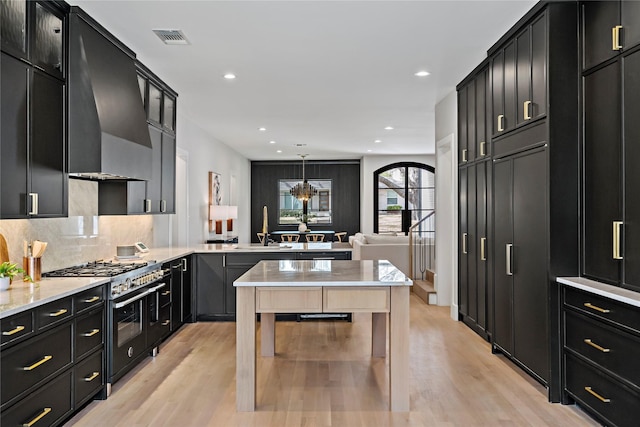 kitchen with dark cabinets, light wood-style floors, visible vents, and range with two ovens