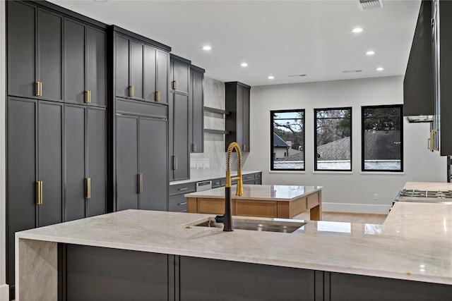 kitchen with sink, paneled fridge, light stone countertops, and kitchen peninsula