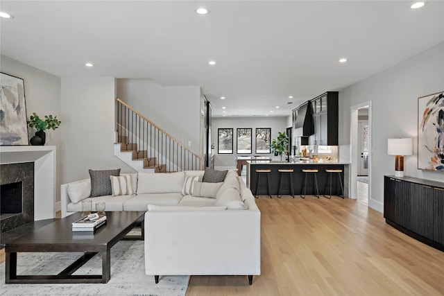 living room featuring light wood-style floors, recessed lighting, stairs, and a fireplace