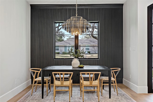 dining space with baseboards, wood finished floors, and a chandelier
