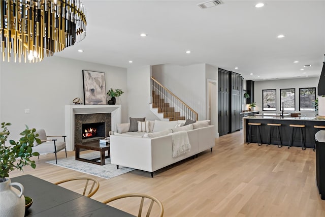 living area featuring light wood-style floors, a premium fireplace, recessed lighting, and visible vents