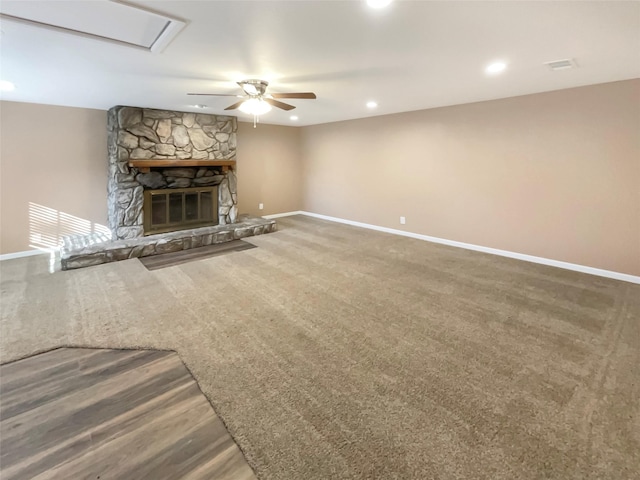 unfurnished living room featuring a stone fireplace and ceiling fan