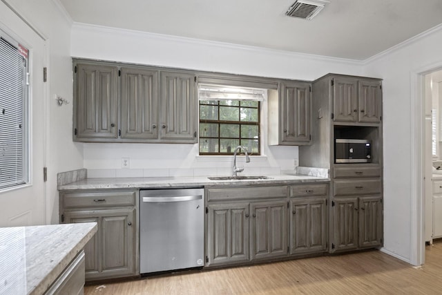 kitchen with sink, light wood-type flooring, ornamental molding, stainless steel appliances, and light stone countertops