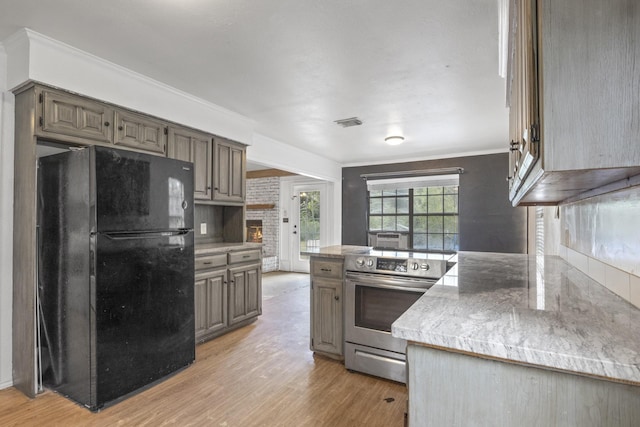 kitchen with crown molding, a brick fireplace, light wood-type flooring, black refrigerator, and stainless steel electric stove