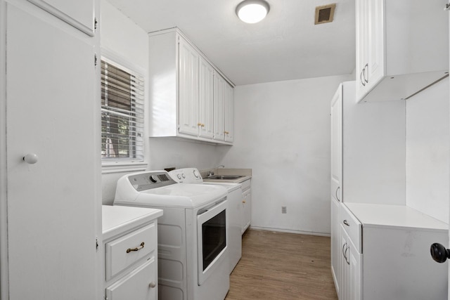 washroom with separate washer and dryer, cabinets, and light wood-type flooring