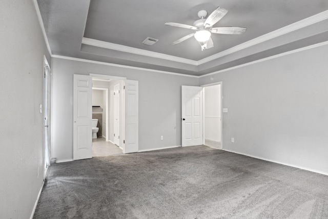 unfurnished bedroom with crown molding, ceiling fan, carpet flooring, connected bathroom, and a tray ceiling