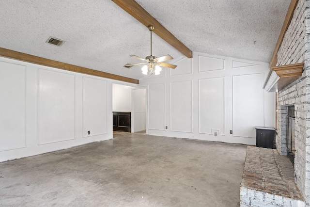 unfurnished living room with concrete flooring, a fireplace, lofted ceiling with beams, ceiling fan, and a textured ceiling