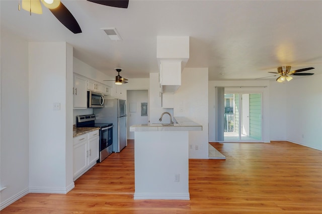 kitchen featuring appliances with stainless steel finishes, kitchen peninsula, light hardwood / wood-style floors, and white cabinets