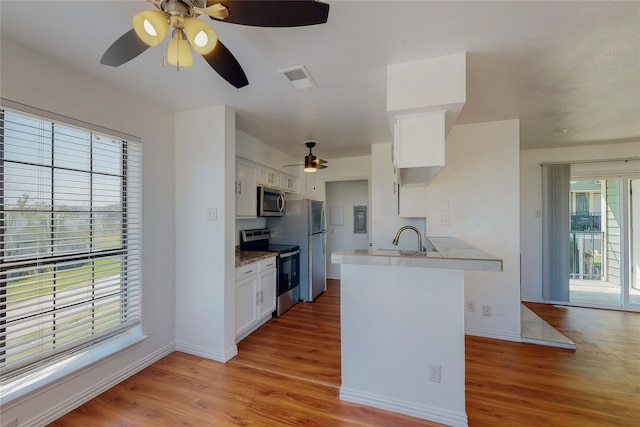 kitchen featuring stainless steel appliances, white cabinetry, light wood-type flooring, and kitchen peninsula