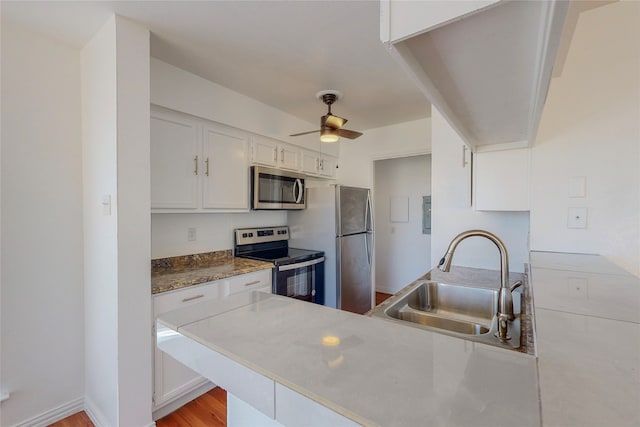 kitchen featuring appliances with stainless steel finishes, white cabinetry, sink, ceiling fan, and kitchen peninsula