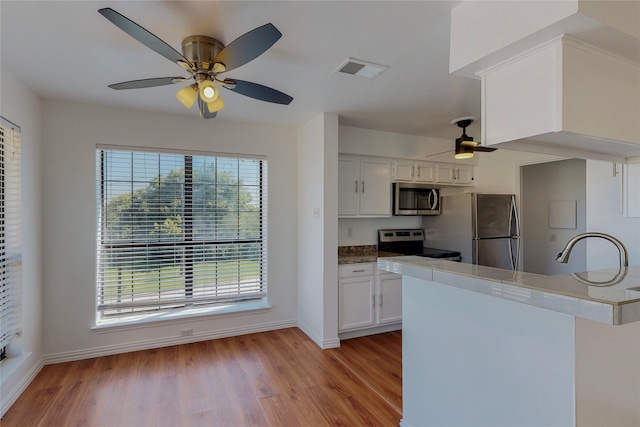 kitchen featuring sink, light hardwood / wood-style flooring, white cabinetry, stainless steel appliances, and kitchen peninsula