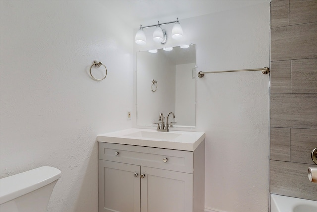 bathroom featuring vanity, toilet, and a washtub