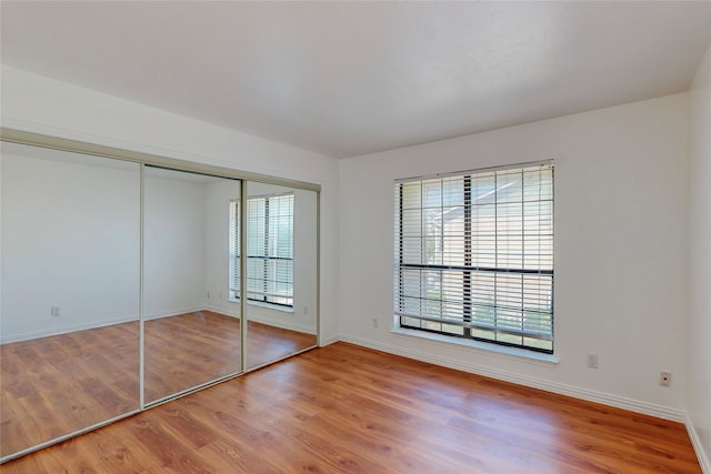 unfurnished bedroom featuring wood-type flooring and a closet