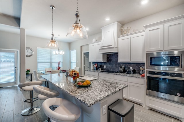 kitchen with appliances with stainless steel finishes, white cabinets, and decorative light fixtures