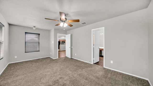 unfurnished bedroom featuring connected bathroom, ceiling fan, and dark colored carpet