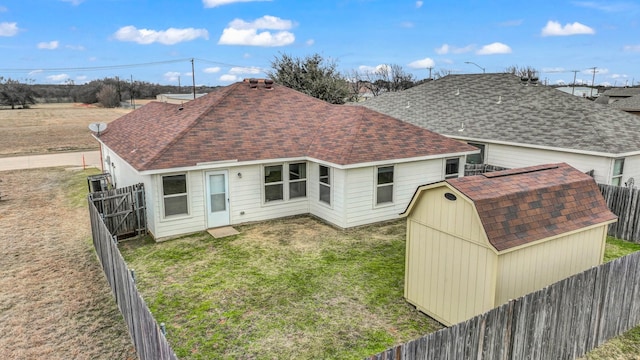 rear view of house with a shed and a lawn