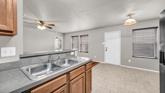 kitchen with decorative light fixtures, sink, light tile patterned floors, ceiling fan, and a textured ceiling