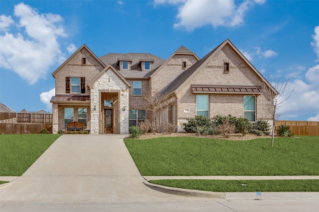 view of front of home featuring a standing seam roof, brick siding, a front lawn, and fence